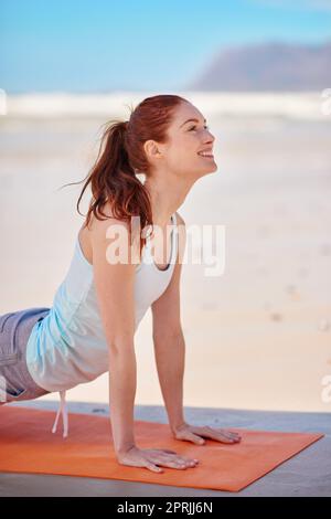 Schaffen Sie ein Leben, das sich von innen gut anfühlt. Eine junge Frau praktiziert ihre Yoga-Routine am Strand. Stockfoto