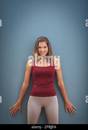 Er ist voller Zuversicht. Porträt einer lächelnden jungen Frau, die vor grauem Hintergrund posiert. Stockfoto