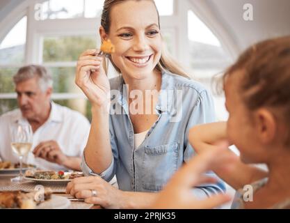 Mutter, Mädchen und Essen im Restaurant, Lächeln und Gabel in der Hand spielen in lustigen Momenten mit dem Kind. Mutter, Kind und glücklich beim Mittag-, Frühstück oder Abendessen in di Stockfoto