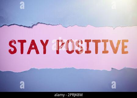 Handschrifttext bleibt positiv, Geschäftskonzept engagiert sich in aufmunternden Gedanken sei optimistisch und real Stockfoto