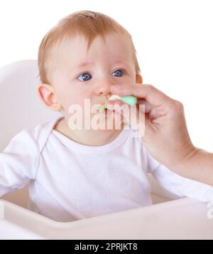 Das Essen zu essen, das Mami zur Verfügung stellt. Ein süßes Baby, das von seiner mutter mit einem Löffel voll Essen gefüttert wird Stockfoto