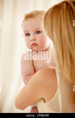 Sicher in den Armen seiner Mütter. Süßer Junge, der von seiner Mutter gehalten wird, während er wegschaut Stockfoto