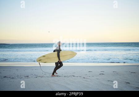Strand, Wasser und Brandung eines Mannes auf Sand mit Surfbrett, der morgens im Freien an der Küste des Ozeans spaziert. Männlicher Surfer läuft mit Longboard in Costa Ric Stockfoto
