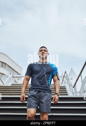 Fitness ist sein Ziel Nummer eins. Low-Angle-Aufnahme eines männlichen Läufers, der auf einer Treppe in der Stadt steht. Stockfoto