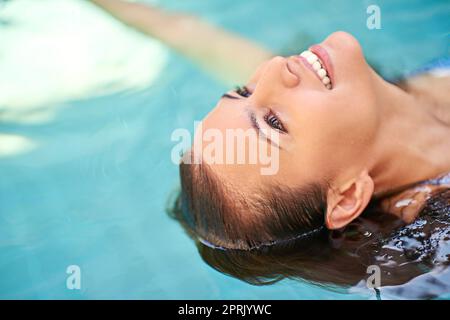 Eine junge Frau, die sich im Pool in einem Spa entspannt. Stockfoto