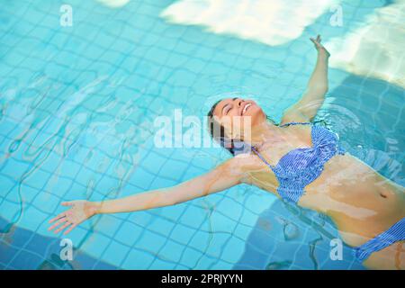 Schweben in das große Blau. Eine junge Frau, die sich im Pool in einem Spa entspannt. Stockfoto