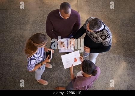 Lassen Sie uns unsere Ideen teilen. High-Angle-Aufnahme einer Gruppe von Arbeitskollegen beim Brainstorming und der Ideenfindung im Kreis im Büro. Stockfoto