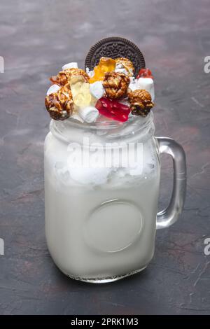 Cocktail für Kinder - milchshake Trinken mit bunten Kaugummi marmelade Würmer und Popcorn Stockfoto
