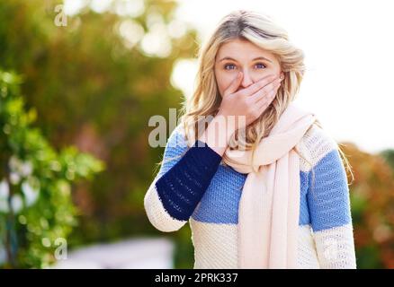 Ich glaube es nicht. Beschnittenes Porträt einer jungen Frau, die mit der Hand über ihrem Mund im Freien steht. Stockfoto