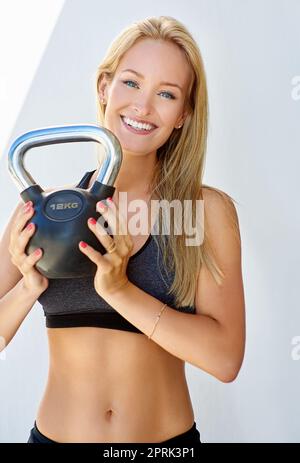 Der beste Weg, um fest und fit zu werden. Beschnittenes Porträt einer jungen Frau mit einer Kesselglocke. Stockfoto