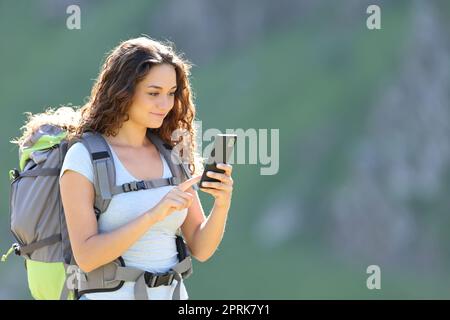 Glücklicher Wanderer, der mit dem Smartphone in den Berg läuft Stockfoto