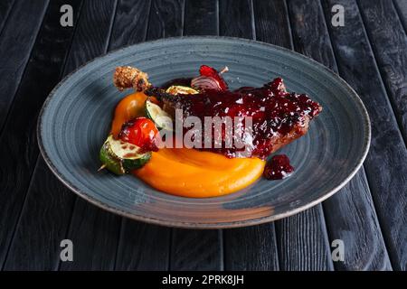 Gebratener Entenschenkel mit Karottenpüree und Zuccini, Pfeffer und Zwiebel auf Holzspieß Stockfoto