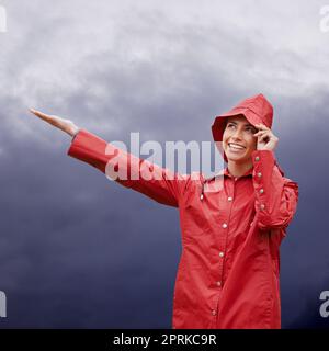 Bei Regen, bei Sonnenschein. Ich bin bereit. Eine attraktive junge Frau, die im Regen steht Stockfoto