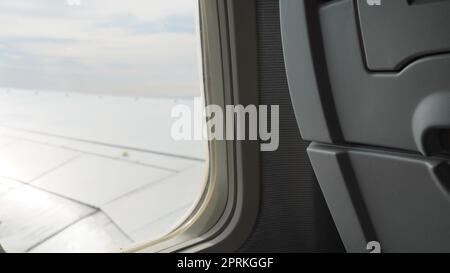 Flügel eines Flugzeuges, Ansicht des Passagiers. Blick durch das Fenster eines Flugzeugs auf seinen glänzenden Flügel Stockfoto