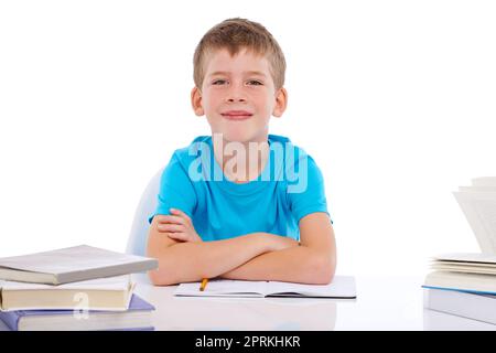 Ich lerne gerne hart. Porträt eines lächelnden Jungen, der mit Büchern vor weißem Hintergrund sitzt Stockfoto