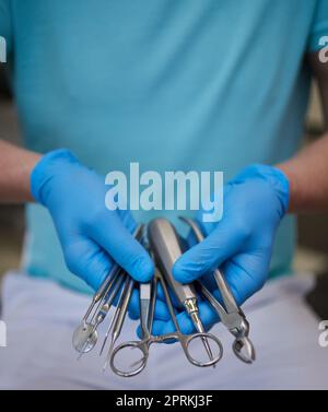 Nahaufnahme der Hände Zahnarzt in sterilen Latexhandschuhen mit Zahnwerkzeugen. Professioneller Zahnarzt verwendet spezielle sterilisierte medizinische Instrumente in modernen Arbeitszimmer Stockfoto