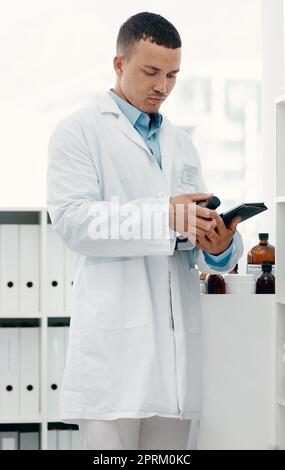 Die Medizin, die Wunder bewirkt. Ein junger Wissenschaftler, der ein digitales Tablet benutzt, während er Medikamente im Labor analysiert Stockfoto