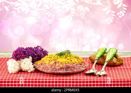 Traditioneller russischer Salat mit dem Namen Hering unter einem Pelzmantel. Traditionelle russische Küche auf einem rustikalen Tisch mit abstrakten Blumen. Konz Stockfoto