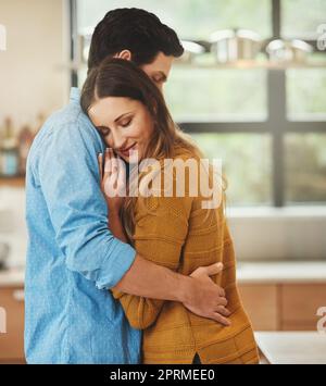 Sie sind so verliebt. Ein liebevolles junges Paar umarmt sich in ihrer Küche. Stockfoto