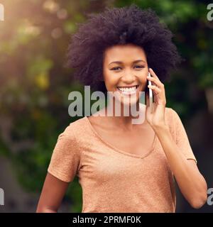 Ich fühle mich glücklich und verbunden in der freien Natur. Eine junge Frau, die auf ihrem Handy spricht, während sie den Tag draußen verbringt. Stockfoto