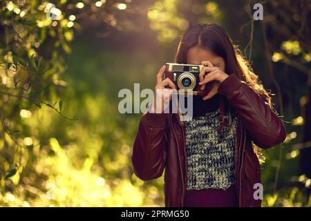 Die Welt durch ein Objektiv ist ziemlich erstaunlich. Ein junges Mädchen, das mit einer Vintage-Kamera im Freien fotografiert. Stockfoto