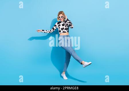 Großes Foto eines verrückten, fröhlichen Mädchens. Genießen Sie das Tanzen, die Zeit zur freien Verfügung, isoliert auf blauem Hintergrund Stockfoto