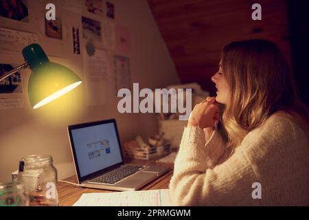 Eine junge Frau, die nachts ihren Laptop in ihrem Schlafzimmer benutzt. Stockfoto