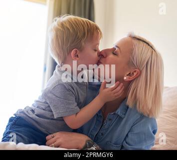 Liebe macht das Leben so schön. Ein kleiner Junge küsst seine Mutter zu Hause. Stockfoto