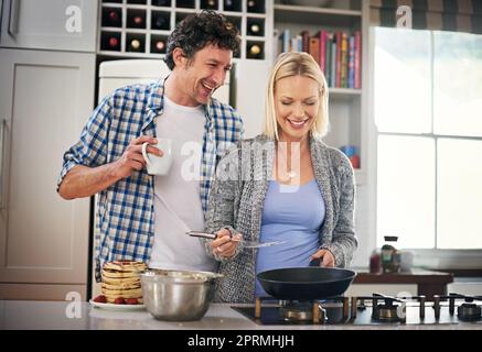 Was kocht, gut aussehend. Ein glückliches Paar, das zu Hause zusammen Frühstück macht. Stockfoto