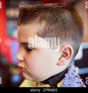 Dieses wird etwas nehmen, das sich an...Nahaufnahme eines kleinen Jungen, der einen Haarschnitt an einem Friseur erhält. Stockfoto