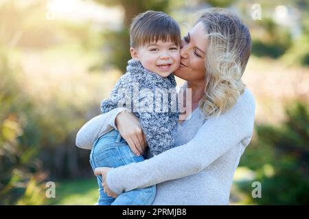 Sie teilen eine unzerbrechliche Bindung, die durch so viel Liebe definiert ist. Eine Mutter, die sich mit ihrem kleinen Jungen draußen verbindet. Stockfoto