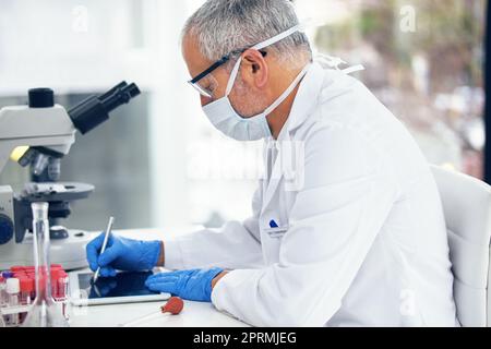 Ein weiterer Durchbruch: Ein Wissenschaftler, der seine Ergebnisse auf einem digitalen Tablet aufzeichnet. Stockfoto