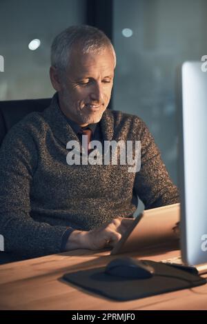 Verspätete Arbeit und Einhaltung von Fristen. Ein reifer Geschäftsmann arbeitet spät im Büro. Stockfoto