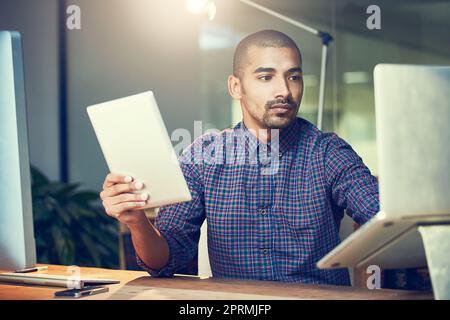 Schauen Sie sich nicht die Zeit an, erledigen Sie einfach die Arbeit. Ein junger Designer, der spät in einem Büro arbeitet. Stockfoto