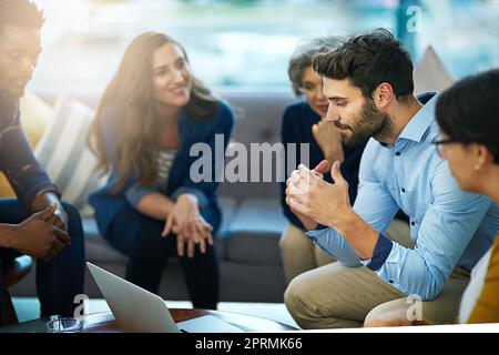 Für dieses Projekt brauchen wir alle Hands-on-Deck. Ein Team von kreativen Geschäftsleuten, die im Büro um einen Laptop herum Brainstorming. Stockfoto