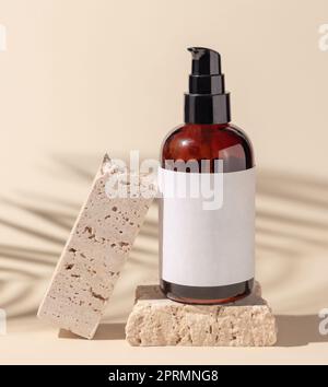 Glaskosmetik, eine Pumpflasche auf Stein auf Hellbeige. Palmenblätter harte Schatten. Label Modell Stockfoto