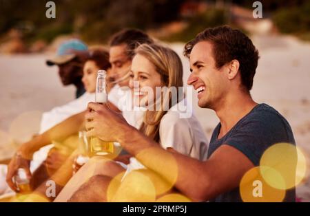 Naturgeschenke mit schönen Menschen genießen. Eine Gruppe von Freunden, die zusammen am Strand sitzen Stockfoto