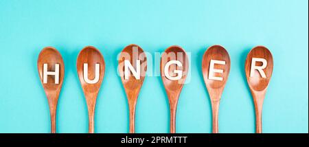 Hunger steht in deutscher Sprache auf den Holzlöffeln, Lebensmittelknappheit und Hunger wegen des Krieges und der Inflation, politische Frage Stockfoto