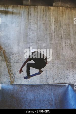 Ein junger Mann macht Tricks auf seinem Skateboard im Skatepark. Stockfoto