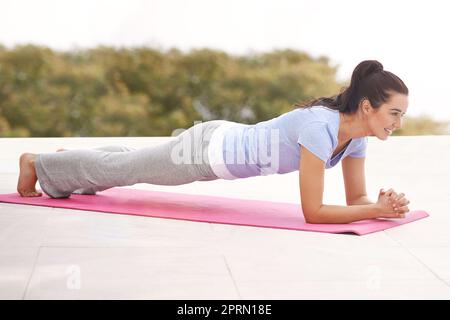 Ihr Herz zu arbeiten. Ganzkörperaufnahme einer jungen Frau, die im Freien Yoga macht. Stockfoto