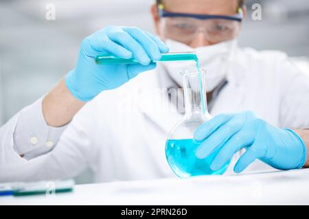 Gefährliche Mischung. Nahaufnahme eines Chemikers, der Chemikalien zusammengießt. Stockfoto