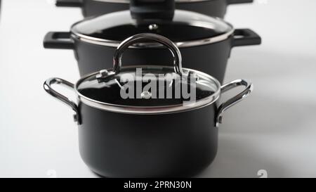 Set aus schwarzen Töpfen auf weißem Hintergrund. Utensilien zum Kochen Stockfoto