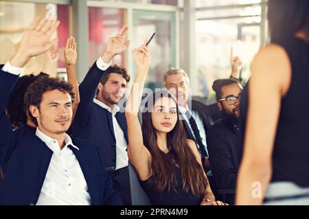 Hier erfahren Sie, wie Sie Ihr Geschäft verbessern können. Geschäftsleute stellten während eines Seminars Fragen Stockfoto