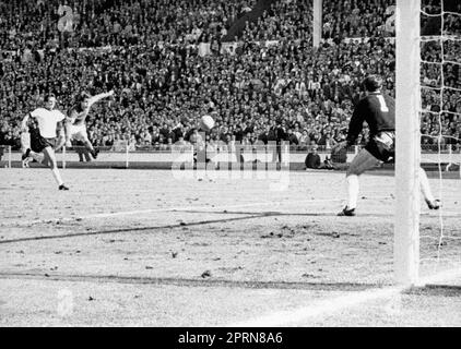 Dateifoto vom 30.-07-1966 von Geoff Hurst aus England schießt hinter dem deutschen Torwart Hans Tilkowski vorbei und schießt in Wembley das Endziel des Weltmeisterschaftsfinales gegen Westdeutschland. Sie denken, es ist vorbei... Englands Geoff Hurst hat es hinter dem deutschen Torwart Hans Tilkowski geschafft, England in den letzten Sekunden der Verlängerung im WM-Finale 1966 in Wembley einen Vorsprung von 4-2 über Westdeutschland zu verschaffen. Ausgabedatum: Donnerstag, 27. April 2023. Stockfoto