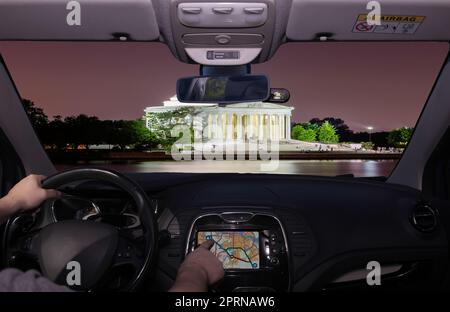 Fahren Sie mit dem Auto, während Sie den Touchscreen eines GPS-Navigationssystems zum Jefferson Memorial in der Nacht in Washington DC, USA, verwenden Stockfoto