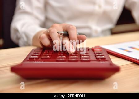 Eine Geschäftsfrau arbeitet mit einem Taschenrechner und erwartet das Budget des Unternehmens Stockfoto