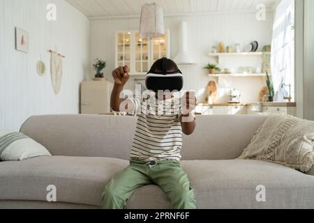 Fokussierter afroamerikanischer Junge fährt Auto und spielt Rennvideospiel in einem Virtual-Reality-Headset. Stockfoto