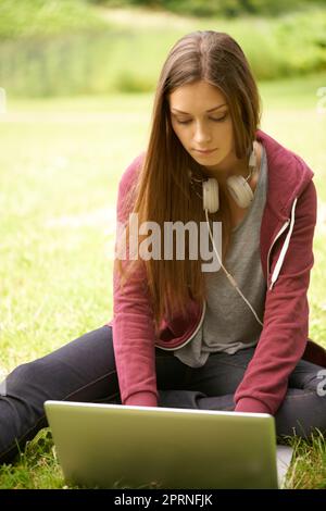 Motiviert und inspiriert von der Natur. Eine reizende junge Frau, die draußen an ihrem Laptop arbeitet Stockfoto