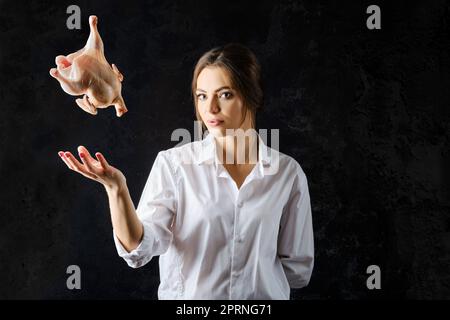 Junge Frau wirft frisches Huhn auf Stockfoto
