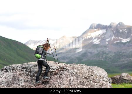 Wanderer, der mit Stöcken auf einem Berg unterwegs ist Stockfoto